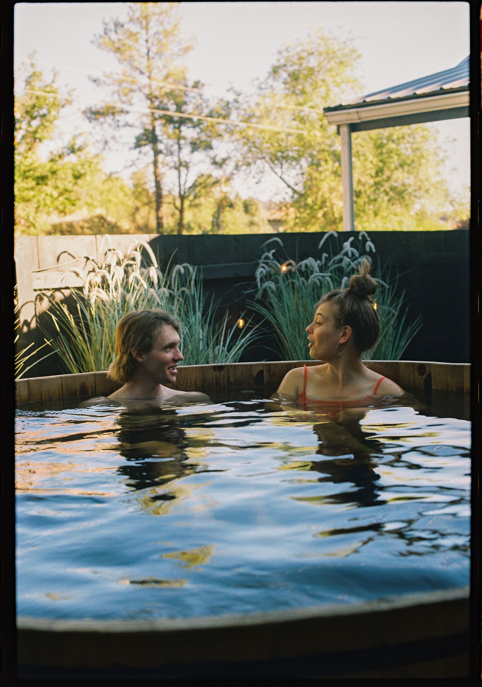Two guests talking in the outdoor cedar hot tub at Adventure Inn Durango