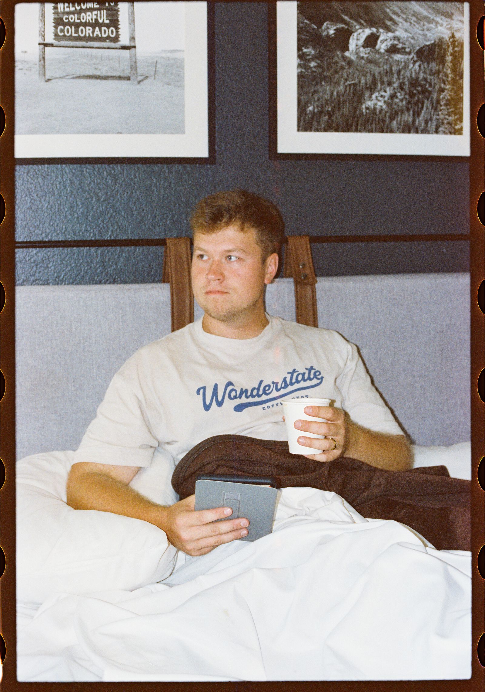 Guest reading with a cup of coffee in bed at Adventure Inn