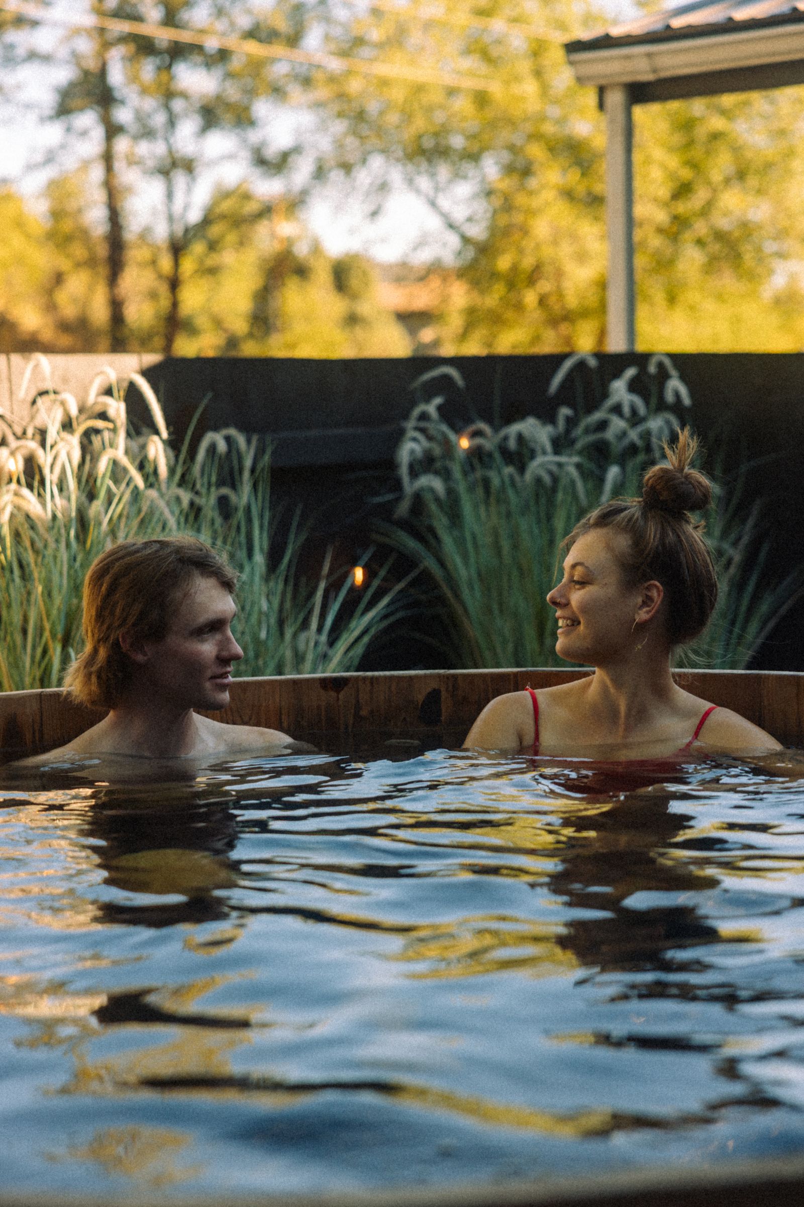 Two guests soaking in the outdoor cedar hot tub at Adventure Inn Durango